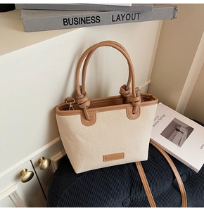 Detail of woven canvas tote bag with brown leather handles and knot decoration