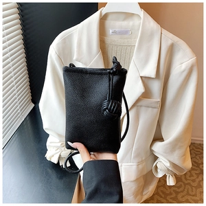Detail of black pebbled leather mini crossbody bag featuring a unique knotted ball charm
