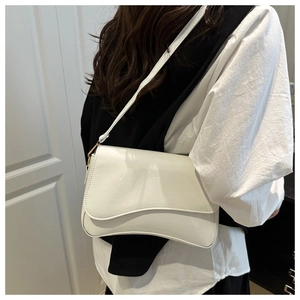 Detailed side view of the white glossy leather shoulder bag with gold metal buckles