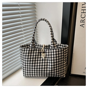 Detail of gingham canvas tote bag featuring a wooden toggle button and jute rope closure