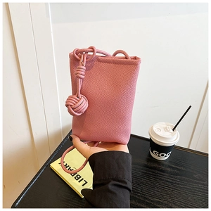 Detailed macro view of pink lychee textured mini phone bag with woven shoulder strap