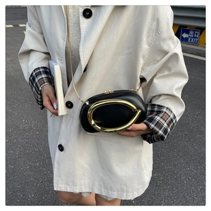 Detail of a black leather oval chain bag featuring a large gold metal U-shaped buckle