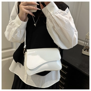 Detail of white patent leather saddle bag with irregular wave flap and gold hardware