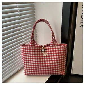 Detail of red and white checkered canvas tote with horn buckle and rope closure