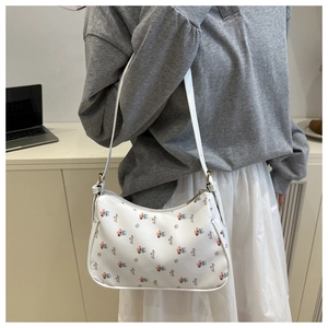 Detail shot of white shoulder bag with floral print and elegant cursive typography