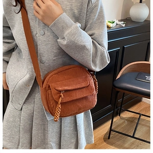 Detail of brown corduroy crossbody bag texture and adjustable strap on a model