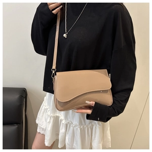 Detail of glossy beige shoulder bag featuring unique irregular flap and fine stitching
