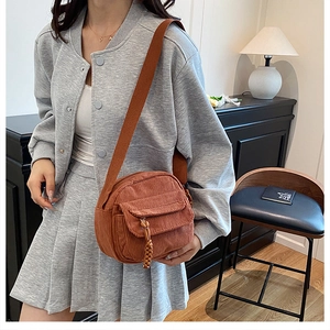 Close-up of caramel corduroy crossbody bag with textured fabric and woven zipper pull
