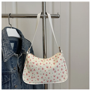 Detail of white baguette bag featuring cherry prints and golden zipper closure