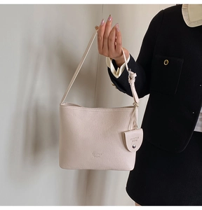 Detail of beige lychee leather crossbody bucket bag with mini pouch and thin strap