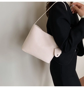 Detail of cream white lychee leather bucket bag with brand logo and side pendant