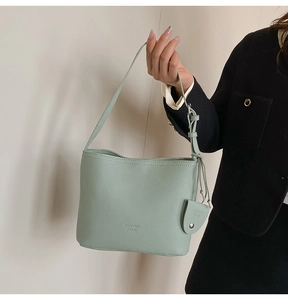 Detail of mint green lychee pattern leather bucket bag with triangle coin purse charm