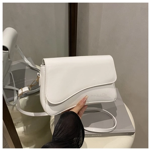 Close-up of minimalist white PU leather crossbody bag with asymmetrical flap and gold hardware