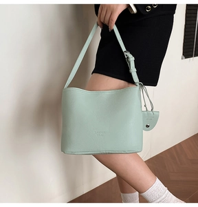 Detail of mint green leather bucket bag showing litchi texture and branded embossing