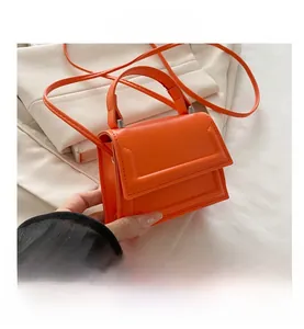 Detailed macro view of vibrant orange faux leather handbag with fine stitching and handle