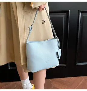 Sky blue litchi pattern bucket bag with adjustable strap and heart-shaped pendant detail