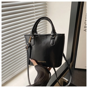 Detail of glossy black bucket bag with gold hardware and FASHION & BAGS lettering