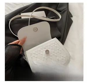 Detail of silver magnetic buckle and quilted leather texture on white saddle bag