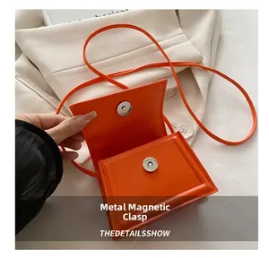 Detail shot of the bright orange crossbody bag featuring a silver magnetic metal clasp