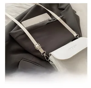 Detail of adjustable silver buckle and woven texture on a white fashion crossbody bag