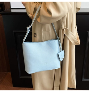 Close-up of light blue leather bucket bag with pebble texture and adjustable strap