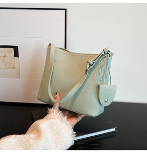 Detail of mint green leather bucket bag showing lychee texture and heart-shaped charm