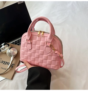 Detailed view of a pink shell-shaped crossbody bag with trendy checkered embossing and gold zippers