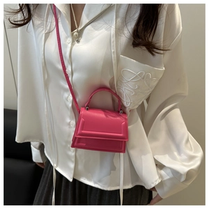 Detail of rose pink mini leather handbag with structured handle and fine stitching on white satin
