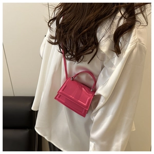 Detail showing fuchsia mini crossbody bag with top handle and sleek leather finish