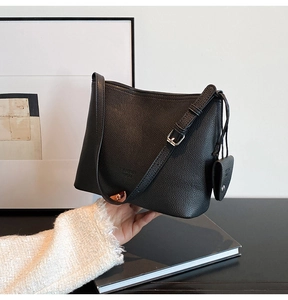 Detail of black leather bucket bag with pebble texture and heart coin purse attachment