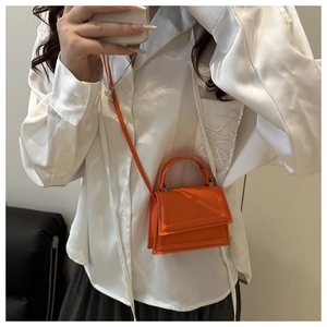 Orange mini crossbody bag with a sleek leather finish and adjustable shoulder strap