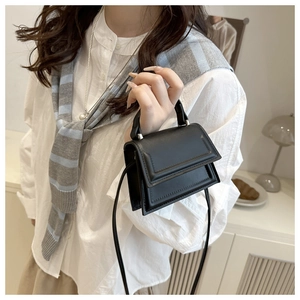 Detail shot of a black minimalist square crossbody bag featuring subtle rectangular framing