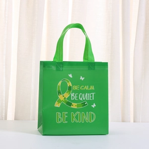 Green non-woven shopping bag with puzzle ribbon print and BE CALM motivational slogan