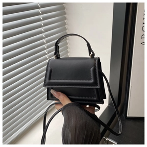 Detail of black mini crossbody bag featuring matte leather texture and silver hardware