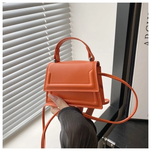Detail of a mini orange crossbody bag with quilted edges and top handle for women