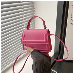 Close-up of a mini rose pink crossbody bag with structured flap and faux leather texture