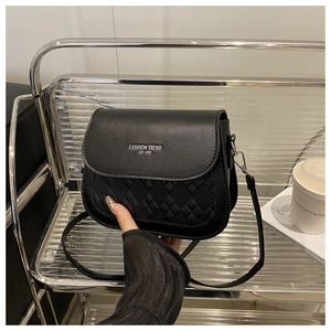 Close-up of black quilted saddle bag with adjustable strap and embossed fashion trend text