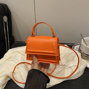Minimalist orange mini crossbody bag with top handle in matte leather for summer