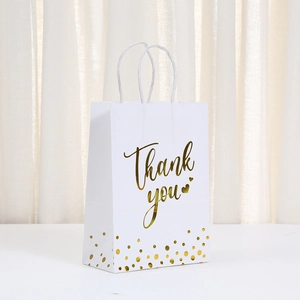 Detalle de bolsa de regalo blanca con texto en pan de oro y puntos dorados