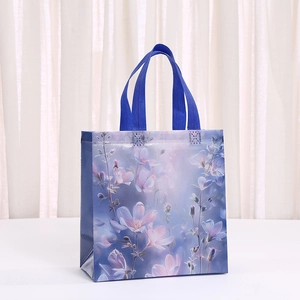 Detalle de bolsa de regalo azul oscuro con motivos florales púrpuras y asas de tejido trenzado