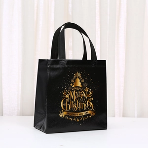 Close-up of black non-woven gift bag with gold Merry Christmas print and handles