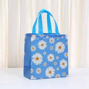 Blue tote bag with daisy print and woven handles for shopping and party gift packaging
