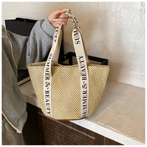 Detail of hand-woven straw tote bag featuring Summer & Beauty printed canvas straps