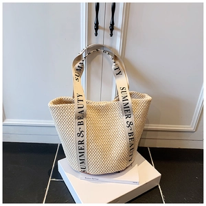 Detail of hand-woven beige tote bag with Summer & Beauty canvas straps on display