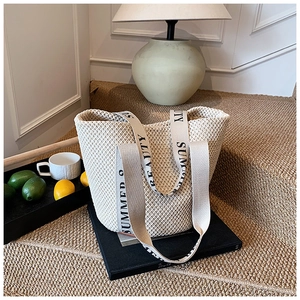 Close-up of woven straw tote bag featuring Summer Beauty canvas straps on a staircase