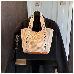 Detail of hand-woven straw tote with leather base and Summer & Beauty printed strap