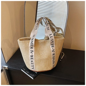 Detail of hand-woven straw tote bag with Summer & Beauty lettered ribbon handle