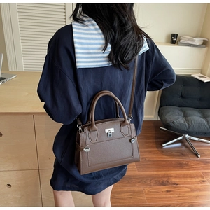 Deep brown leather bag with lychee texture and silver hardware worn by model