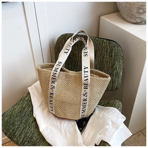 Detail of woven straw tote bag featuring Summer & Beauty printed canvas straps