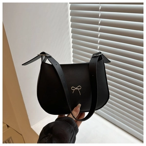 Close-up of matte black crescent bag featuring a silver bow buckle and wide leather strap